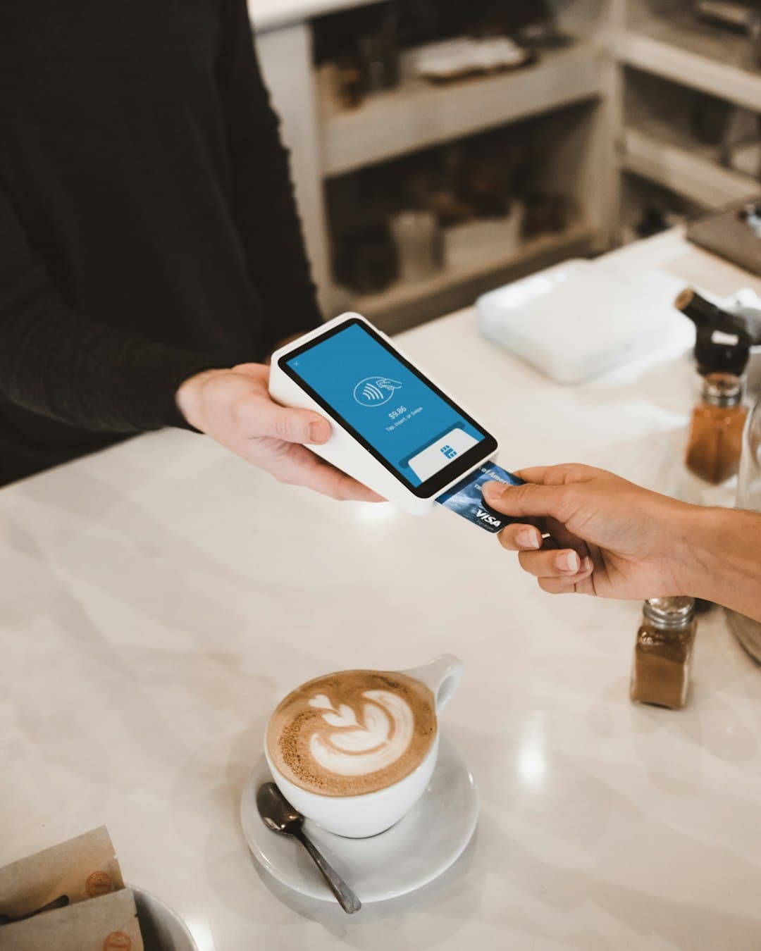 Customer paying by card at a POS terminal at a café counter